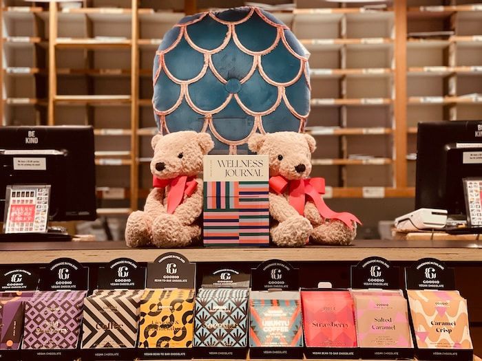 Gift display with two teddy bears, colorful striped item, and patterned boxes on a counter in a shop