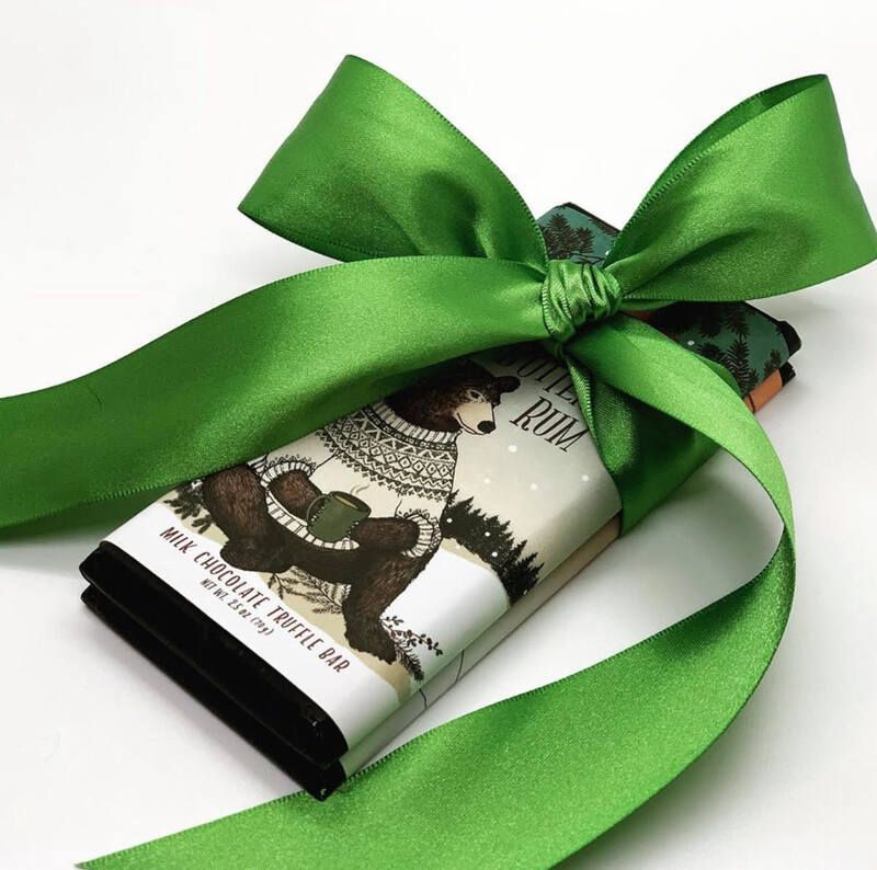 Green ribbon tied around a small bottle of illustrated liquid soap on a white background
