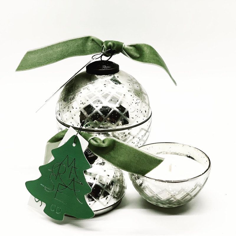 Green ornament with leaf topper and tree tag beside a small clear bowl on a white background