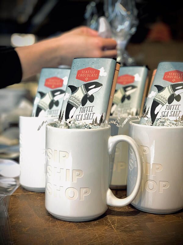 White mugs and milk cartons on a table, with a hand placing a mug in the foreground.