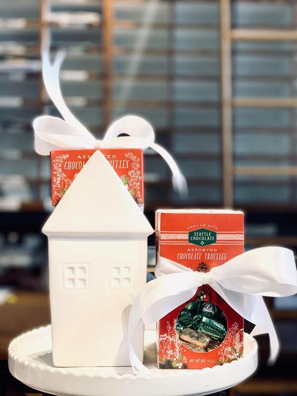 White decorative house with white ribbon and orange-red packaged gifts on a tray