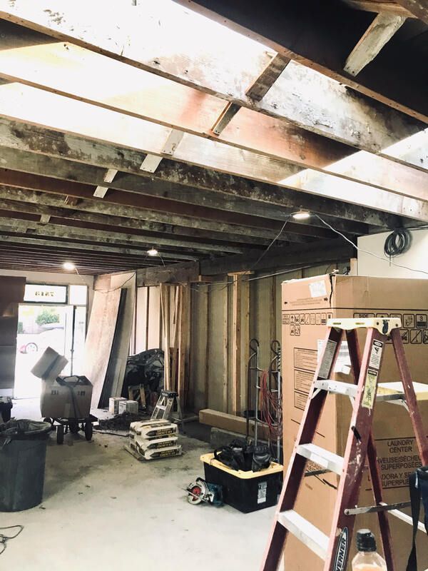 Basement renovation with exposed ceiling beams, tools, and a ladder in a cluttered work area