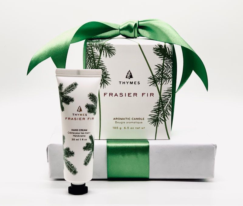 Thymes Frasier Fir gift set with green ribbon and white packaging, scented body care products displayed on white.