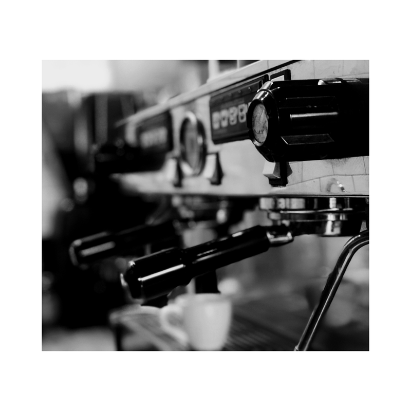 Black-and-white close-up of espresso machine portafilters in a café