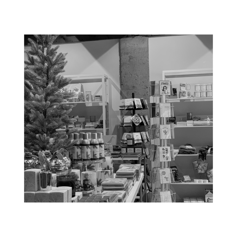 Holiday store display with decorated tree, wrapped gifts, and shelves of ornaments and decor