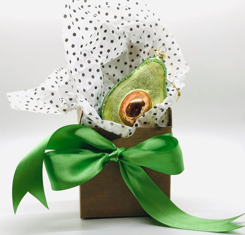Gift box with a green satin bow and polka-dot tissue, holding an avocado half