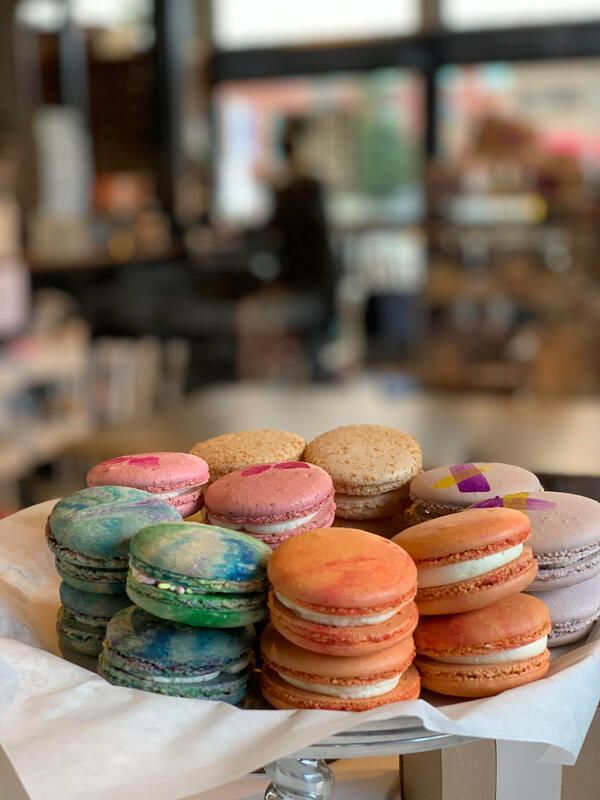 Stack of colorful macarons on a white paper-lined tray in a café.