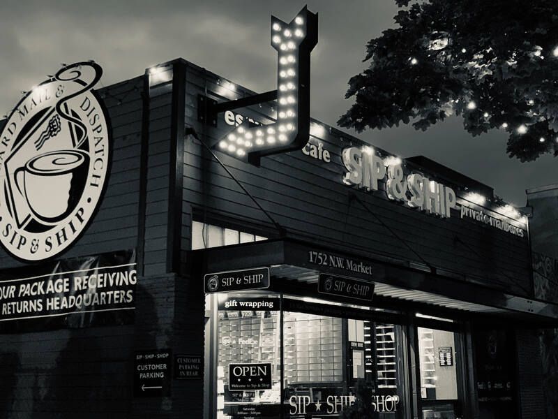 Black-and-white exterior of the Sip Ship bar and restaurant at night, with neon signage and lit windows