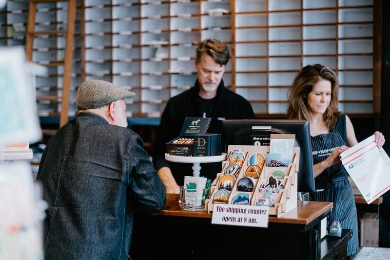 People at a café counter with menus and a barista serving drinks