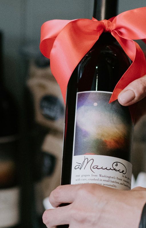 Wine bottle wrapped with a red ribbon and held by hands