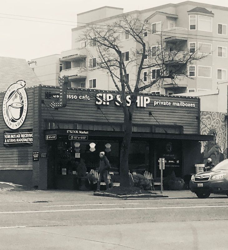 Black-and-white street view of a cafe storefront with people standing outside and a parked car.