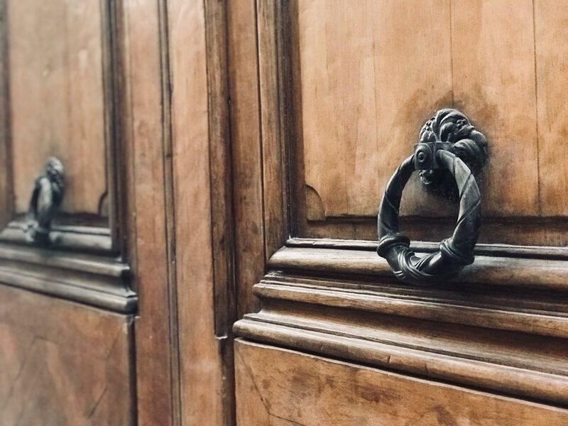 Wooden cabinet doors with ornate dark metal ring handles