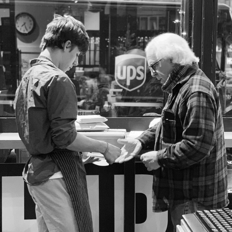 Two people exchanging papers at a UPS counter, with the UPS logo visible in the background.