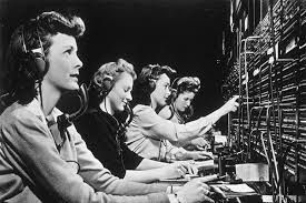 Operators seated at a switchboard, connecting cables in a communications room