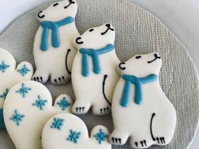 Polar bear cookies with blue scarves and snowflake cookies on a plate