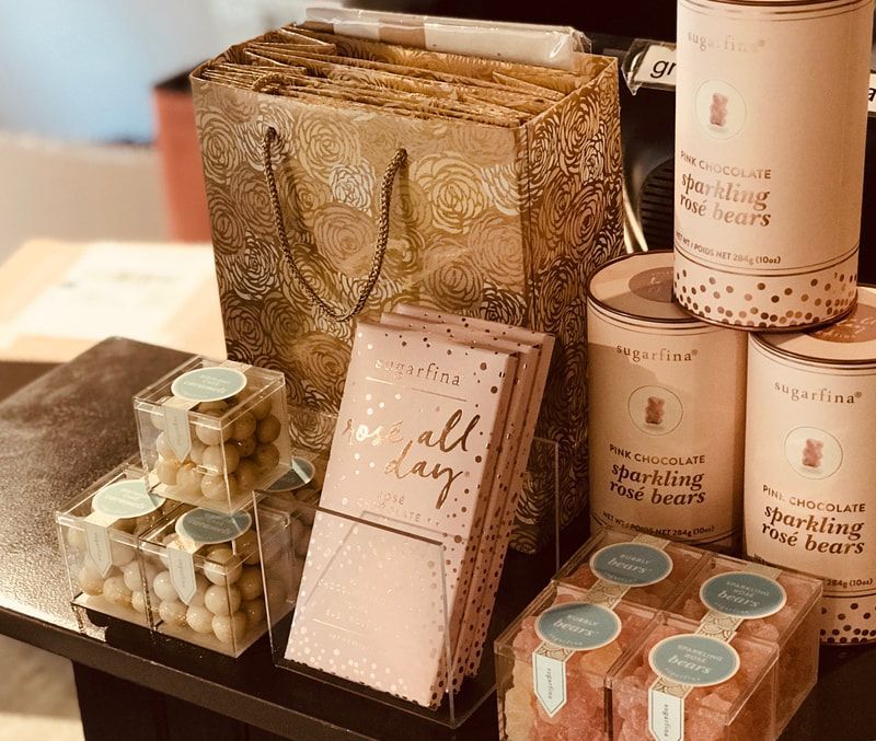 Pastel gift boxes and candles arranged on a table, with a gold decorative bag in the background