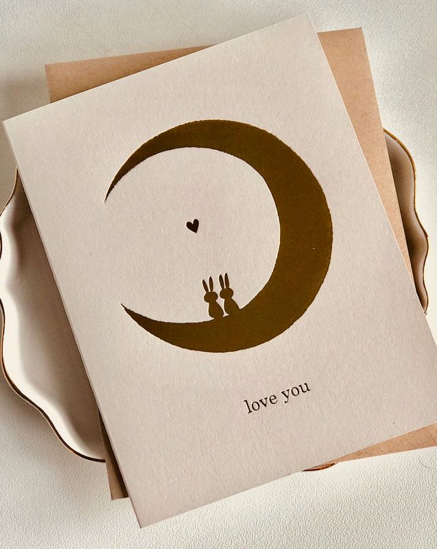 A beige card with a crescent moon, two silhouettes, a small heart, and the words “Love You.”