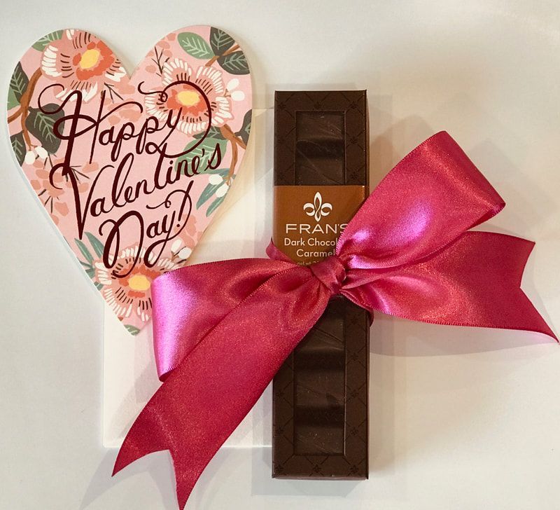 Heart-shaped Valentine card beside a chocolate bar tied with a bright pink ribbon
