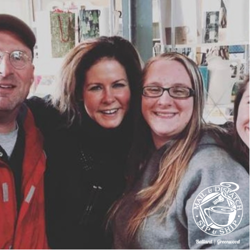 Three smiling people posing indoors, with a partial face at the left edge.
