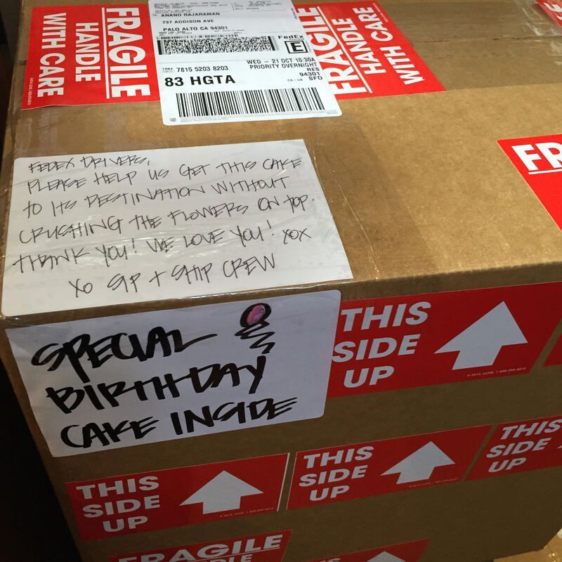 Cardboard shipping box with red fragile labels and a handwritten note: “open with party cafe inside.”