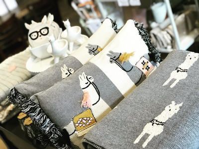 Gray cat-themed pillows and plush toys arranged on a couch, with black-and-white patterned fabric accents