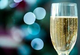 A champagne flute filled with sparkling wine against a blurred blue and green bokeh background