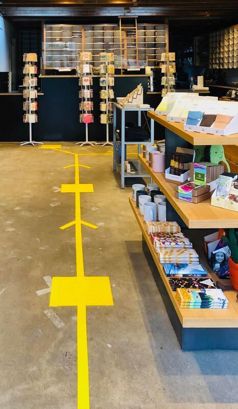 Retail shop interior with a yellow floor guide line leading to display shelves and a counter.
