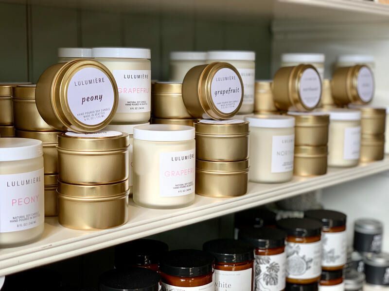 Gold cosmetic tins and jars on store shelves, with small jars and bottles below