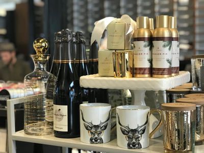 Wine bottles, gold-lidded jars, and white cups displayed on a countertop