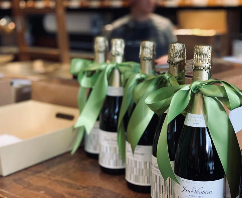 Bottles of sparkling wine with green ribbons on a wooden table in a shop or tasting room