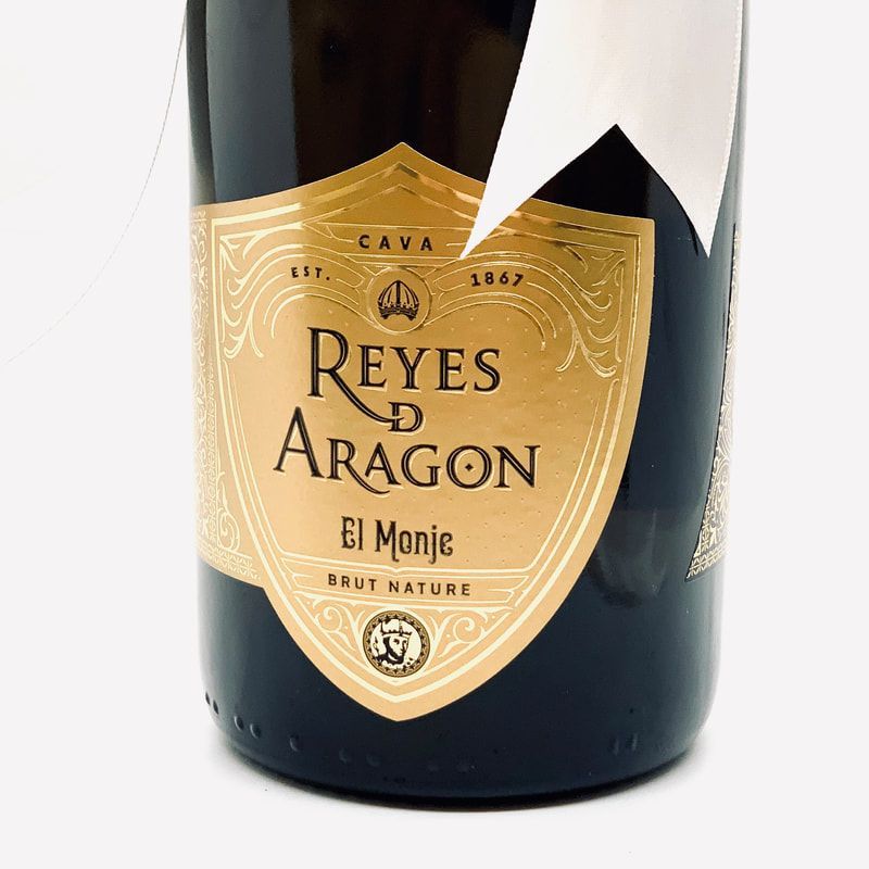 Bottle label for Reyes de Aragón El Monje cava, gold and black with ornate shield design