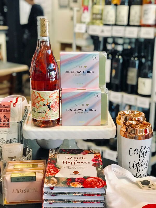 Gift display with wine bottle, pastel boxes, coffee mugs, and chocolates on a table