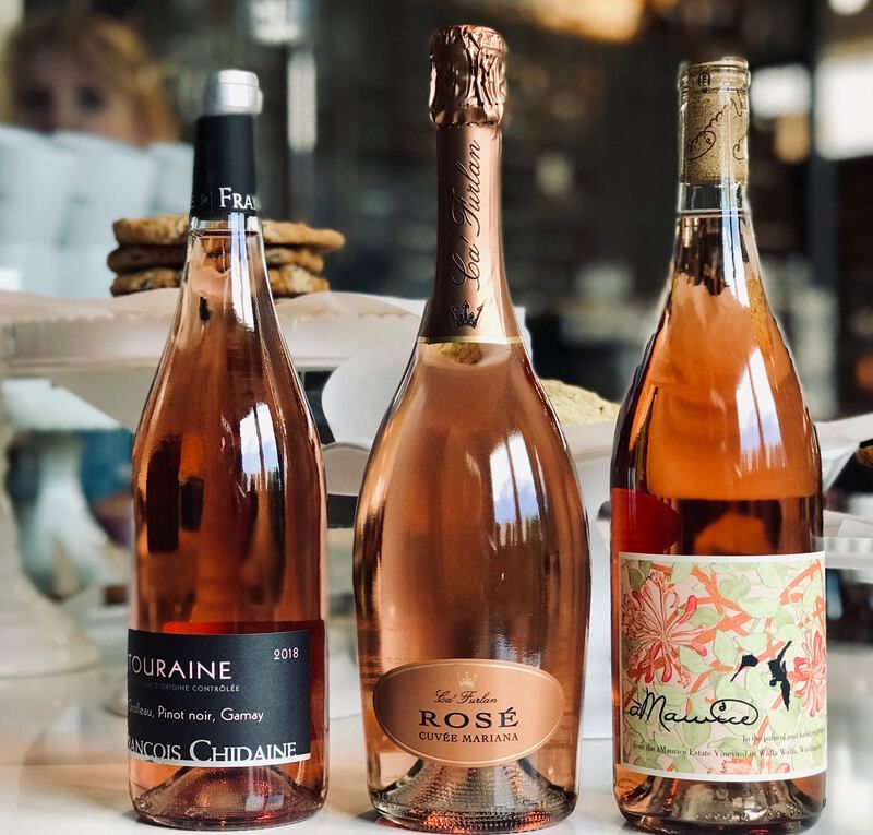 Three rosé wine bottles on a table, with a blurred background and warm amber tones