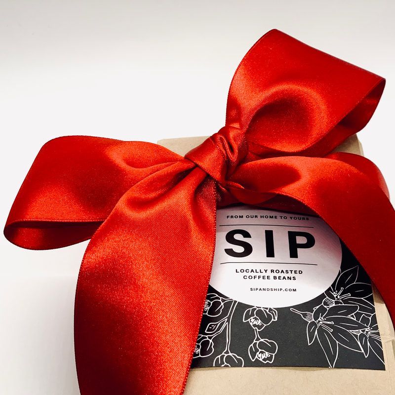 Gift box tied with a shiny red bow, featuring a SIP coffee label.