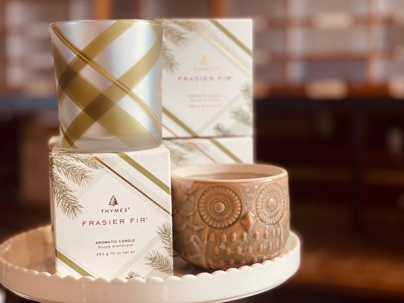 Decorative gold and cream scented candles and boxes on a white scalloped tray