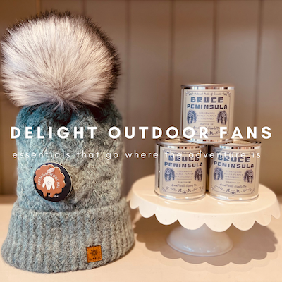 Gray knit beanie with fluffy pom-pom beside Bruce mini candles on a scalloped stand