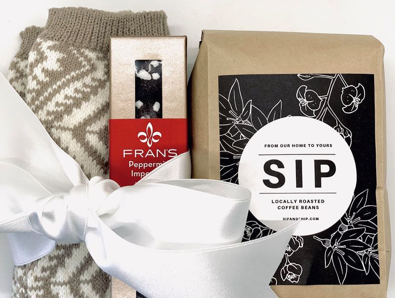 Gift set with a knitted gray scarf, red peppermint tea box, and black SIP tea package tied with a white ribbon.