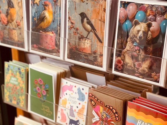 Colorful bird and floral greeting cards displayed on a shelf in a shop