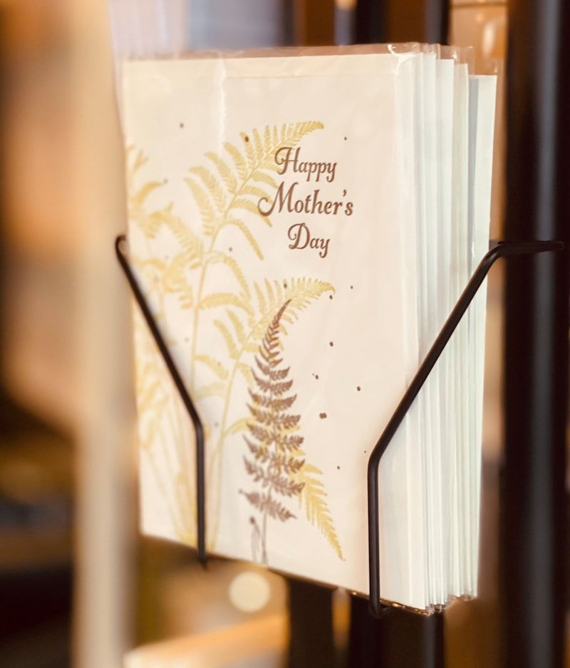 Mother's Day greeting card in a black display holder, with gold fern design and cream background.