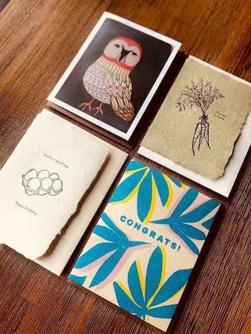Four handmade cards on wood: owl, tree, floral sketch, and a blue “CONGRATS!” card.
