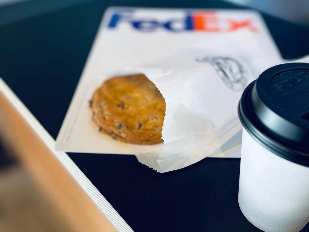 FedEx envelope with a pastry and coffee cup on a dark table