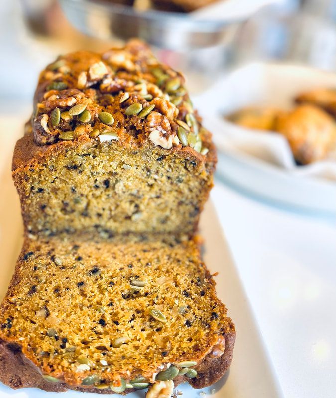 Sliced nut-topped loaf cake with a moist crumb on a white plate