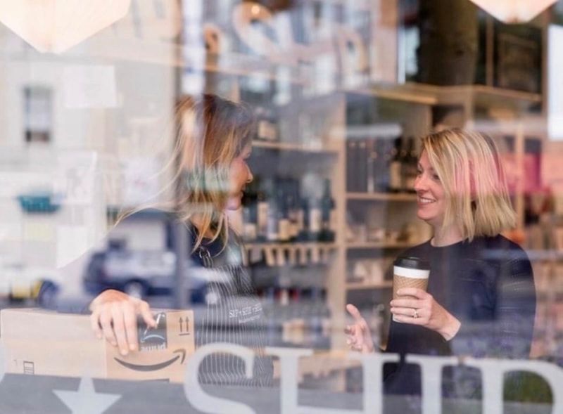 Two people talking in a café, one holding a coffee cup and smiling across the table.