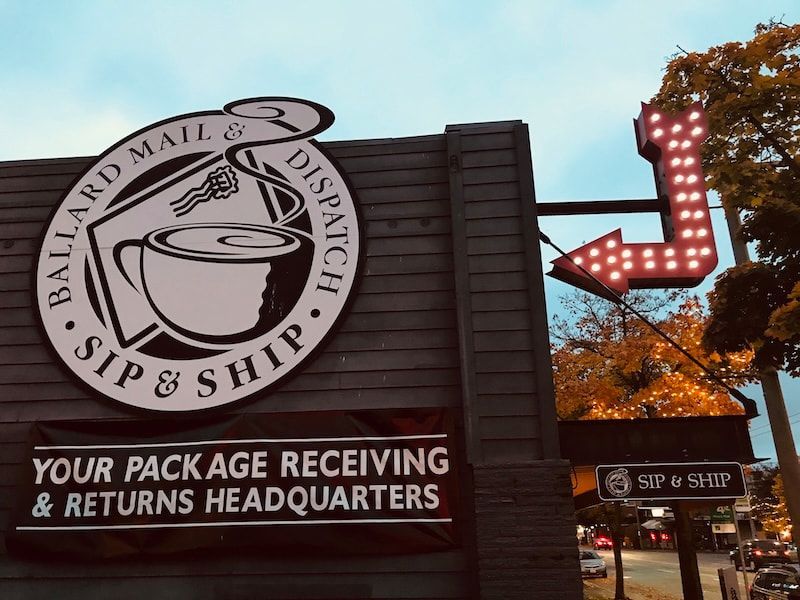 S&P Ship storefront sign with red arrow lights and a banner reading “Your Package Receiving & Returns Headquarters”