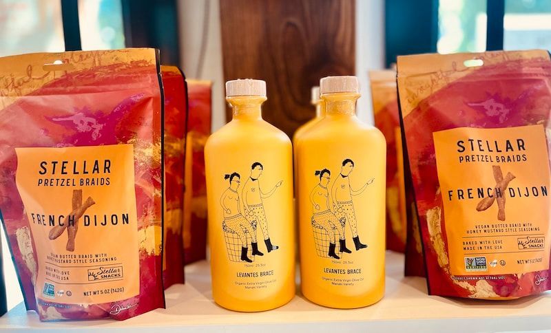 Two yellow bottles and two orange pouches of Stellar drinks on a wooden table, front-facing.