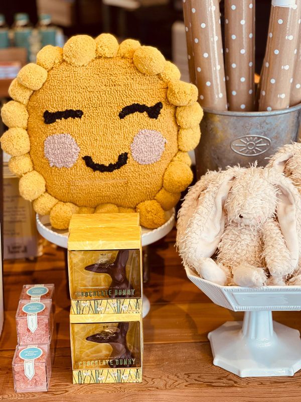 Smiling cookie-faced cake on a stand beside a fluffy white bunny-shaped dessert and sweets on a table