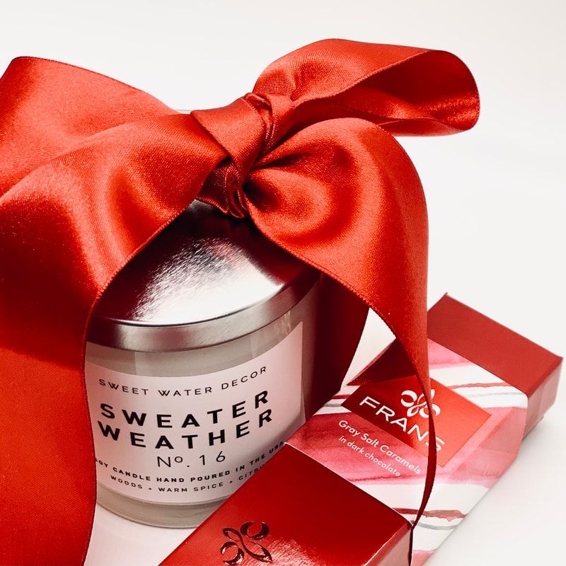 Red gift box and candle jar wrapped with a shiny red ribbon on a white background