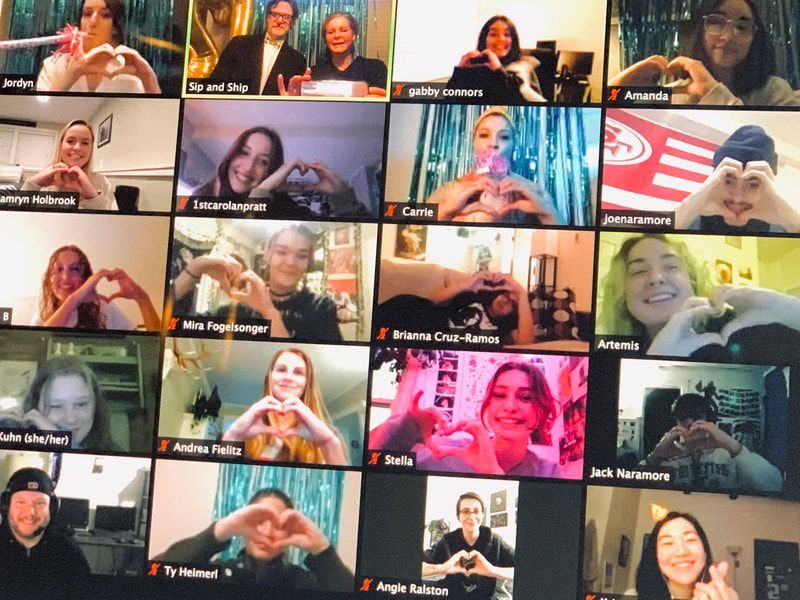 Video call gallery view with many participants in small tiles, some smiling and waving.