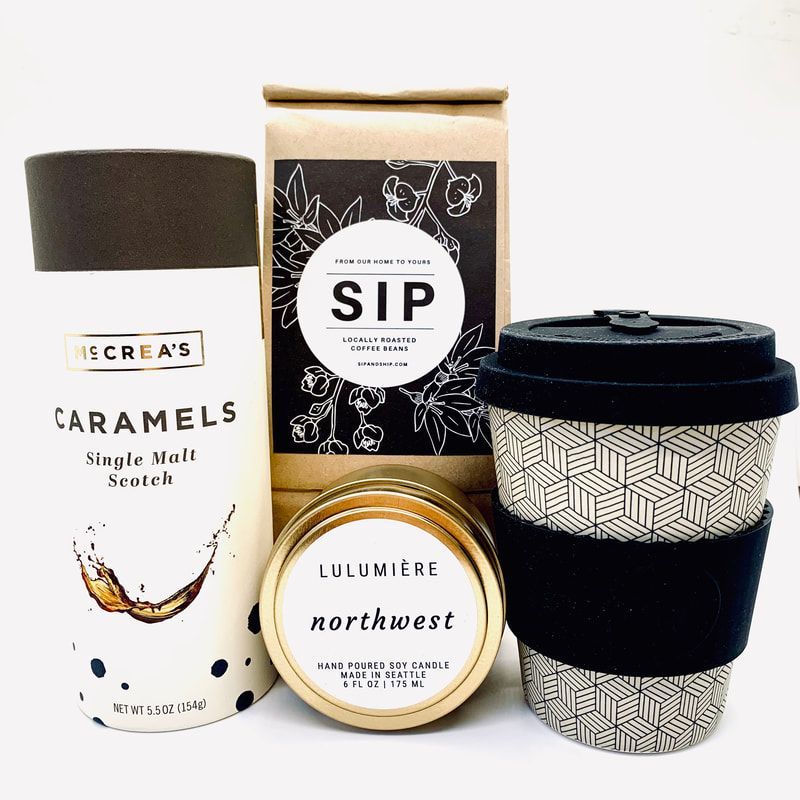 Four assorted scented candles and a black patterned takeaway cup on a white background