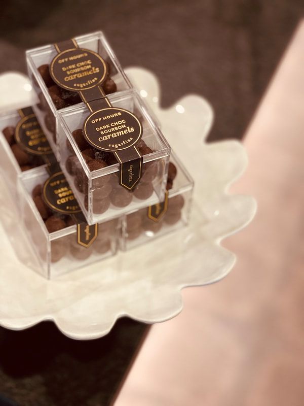 Clear stacked chocolate gift boxes on a white scalloped dish.